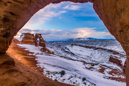 Photo of Delicate Arch through a window in the rocks.
